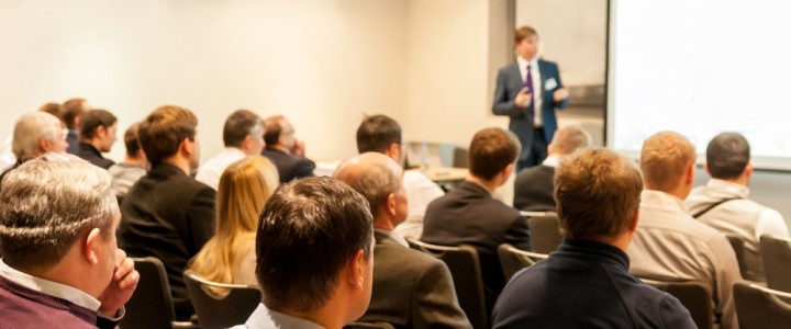 people sitting at the business conference and speaker at the screen
